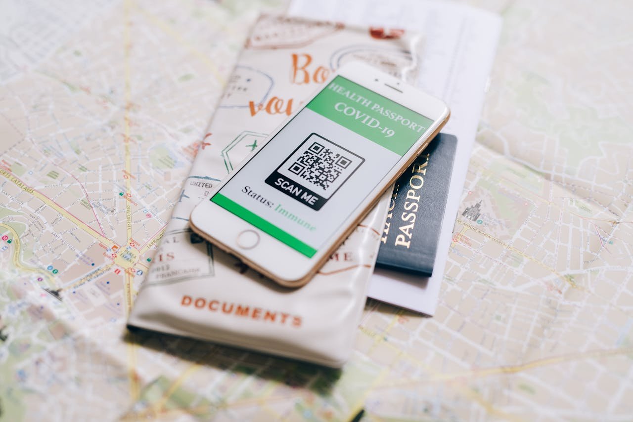 A smartphone displaying a COVID-19 health passport on a map with a travel passport.