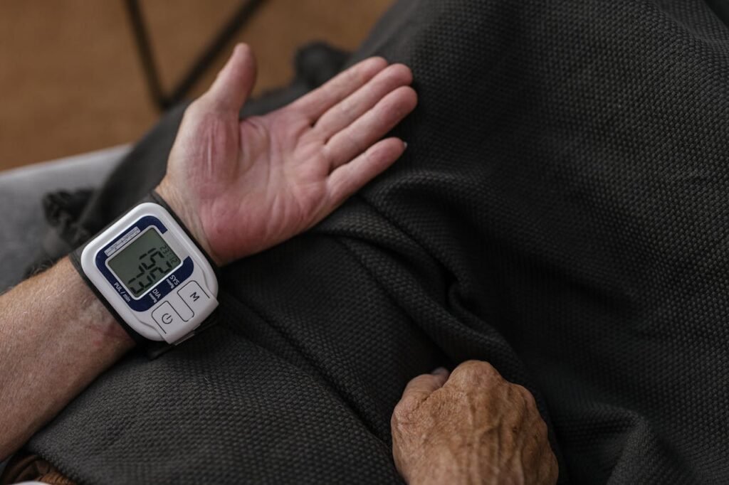 A senior adult using a wrist blood pressure monitor at home, focusing on health management.